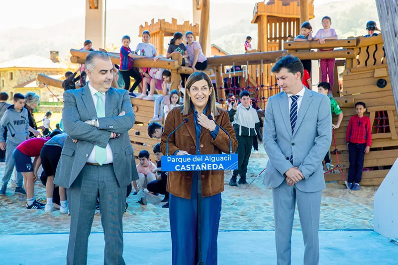 La presidenta, junto con el consejero y el alcalde, interviene en el acto inaugural. Al fondo, alumnos del colegio El Haya, disfrutando de la nueva zona infantil (FOTO: Oficina de Comunicación)